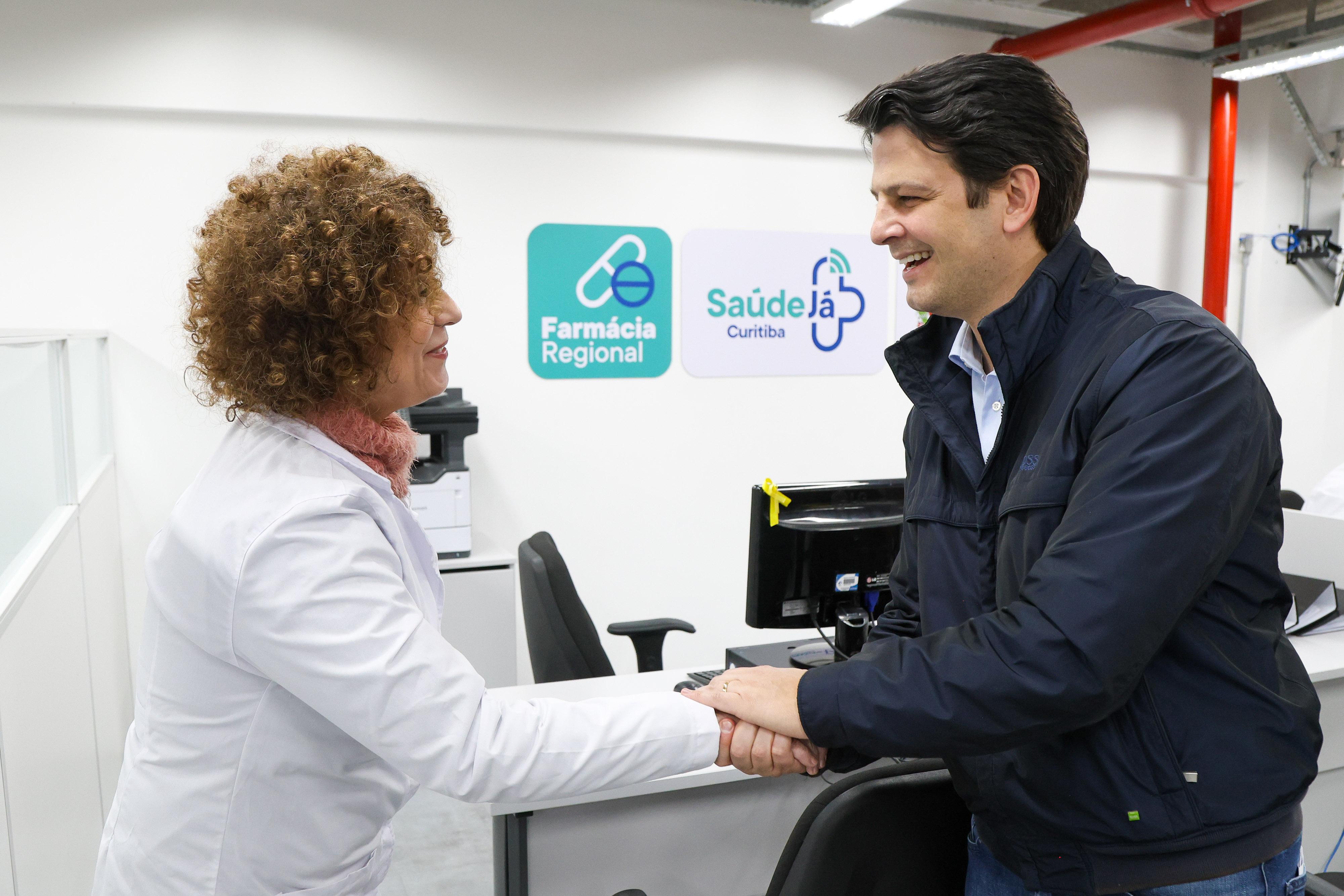 Farmacêutica entrega caixas de medicamentos a uma mulher no balcão da Farmácia Regional da CIC, em Curitiba.