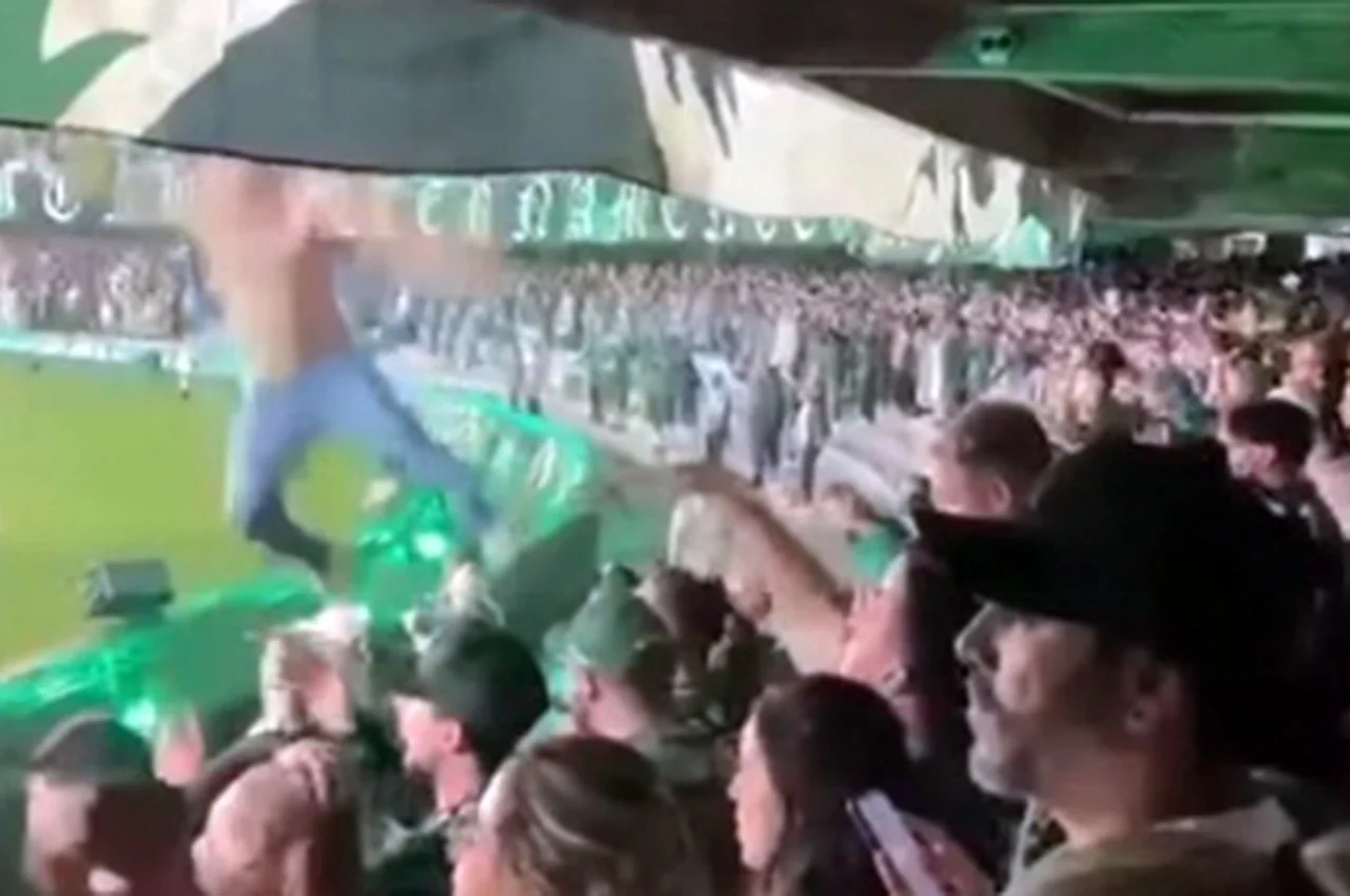 Torcedores reunidos em arquibancada de estádio durante uma partida, com público em pé e grande movimentação no local.