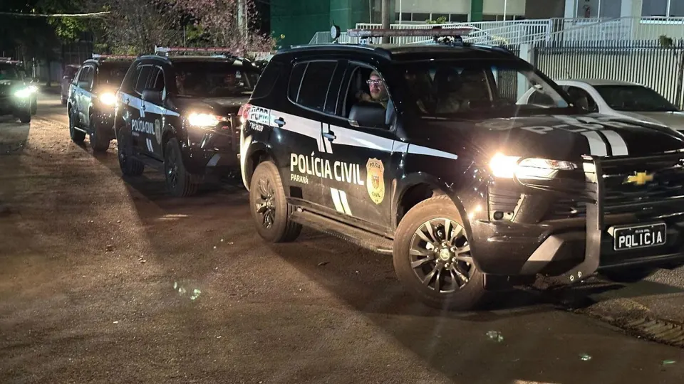 Viaturas da Polícia Civil do Paraná em uma rua durante operação policial noturna.
