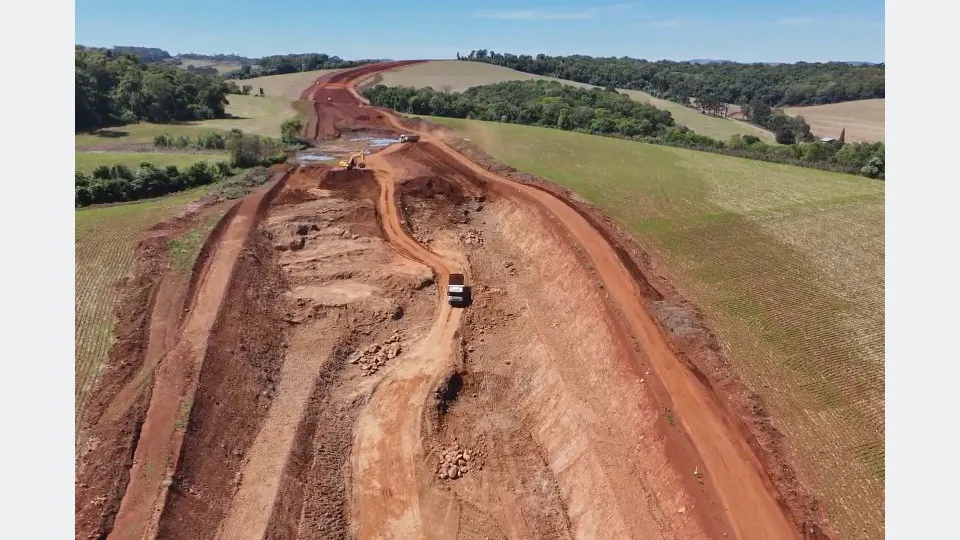 Vista aérea das obras do Contorno Noroeste de Pato Branco, no Paraná, mostrando escavações, movimentação de terra, caminhões e máquinas trabalhando na construção da nova rodovia.
