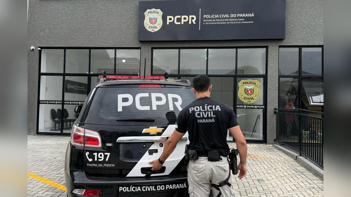 Policial civil ao lado de uma viatura da PCPR estacionada em frente à 6ª Delegacia Regional de Polícia de Piraquara, na Região Metropolitana de Curitiba.