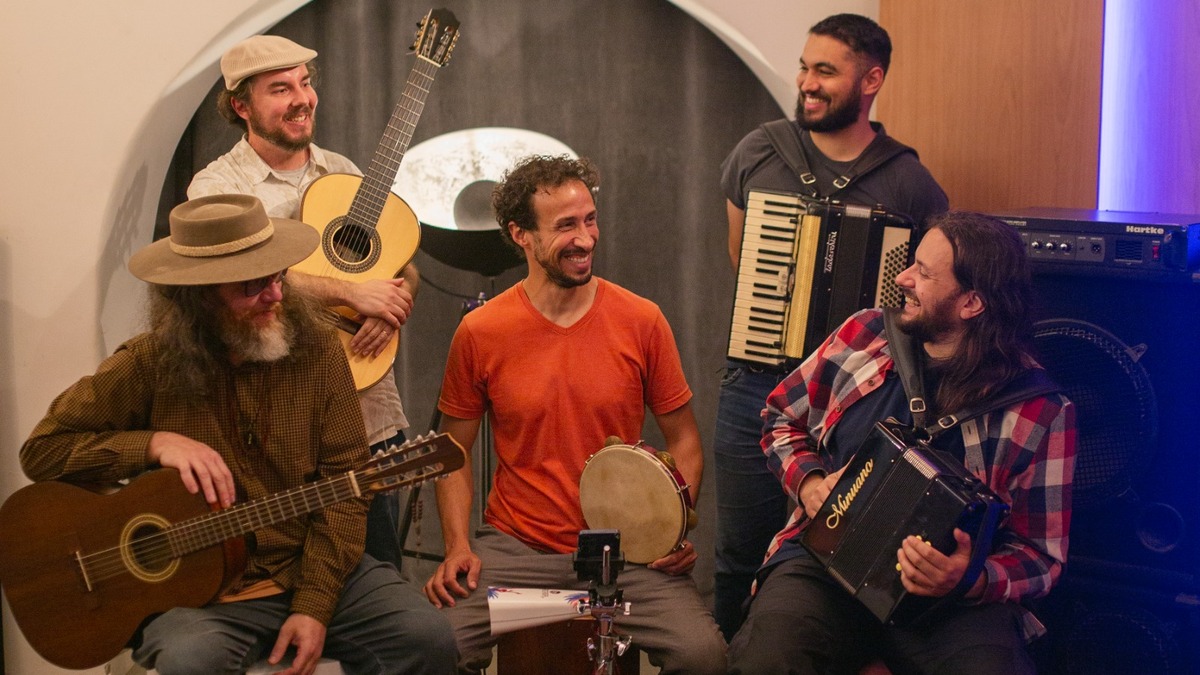 Cinco integrantes do Grupo Caboclo Tingui reunidos com violas, violão, acordeão e instrumentos de percussão.