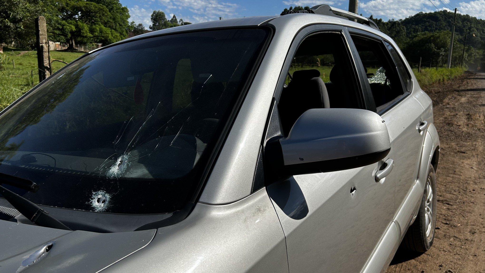Automóvel branco com marcas de disparos na lateral e vidros danificados, fotografado em investigação de tentativa de homicídio em Santo Antônio da Platina, no Paraná.