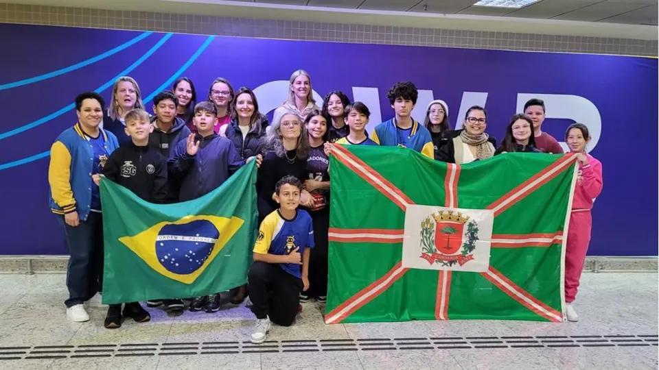 Estudantes da rede municipal de Curitiba com bandeiras do Brasil e de Curitiba após conquistas no Torneio Internacional de Robótica no Chile.