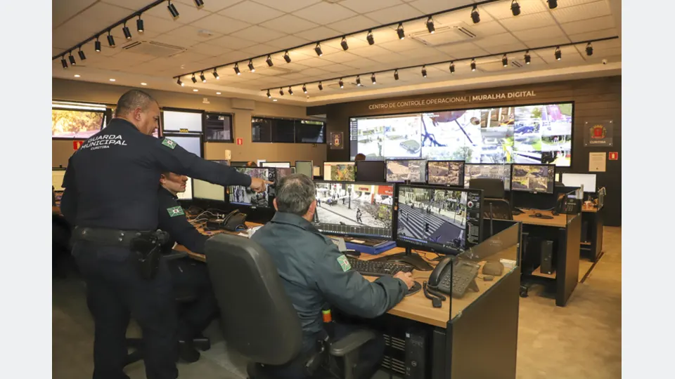 Guardas municipais monitoram câmeras de segurança no Centro de Controle Operacional da Muralha Digital de Curitiba.