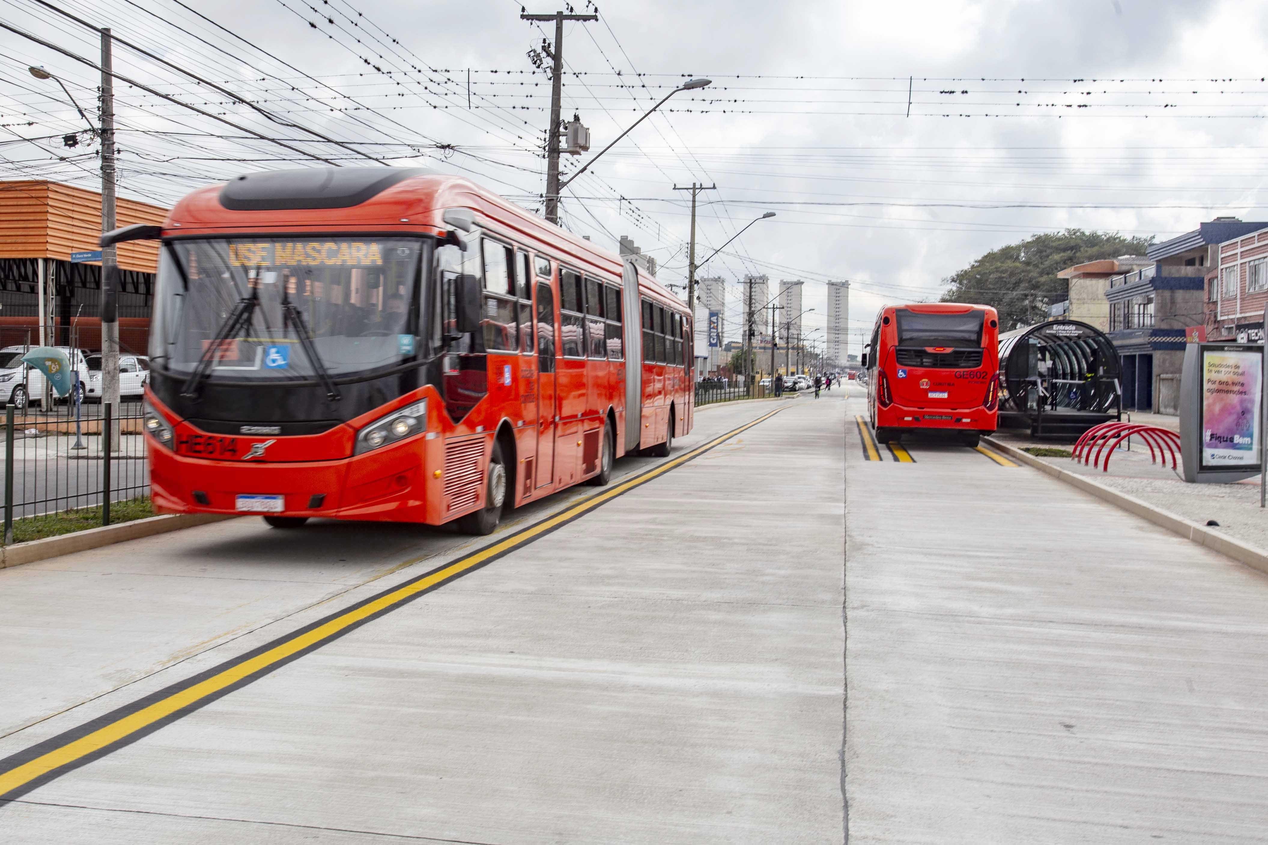 Ônibus vermelho da linha Capão Raso em terminal de Curitiba, com passageiros embarcando, em fotografia de arquivo da Prefeitura.