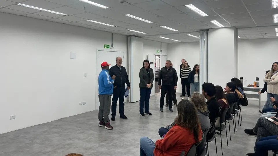 Liderança comunitária fala diante de representantes públicos e moradores durante reunião sobre mudanças nas escolas municipais de Curitiba, na CIC, em 29 de outubro de 2026.