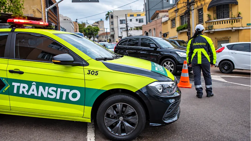 Agente municipal e viatura de fiscalização de trânsito de Curitiba em imagem institucional usada para informar bloqueios previstos no Bacacheri.