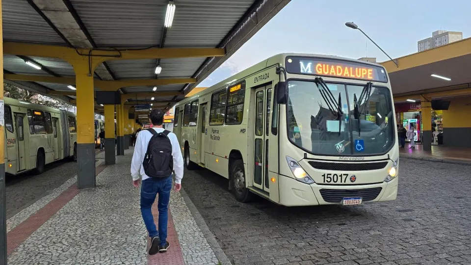 Ônibus metropolitano branco e amarelo, identificado como Pinhais, estacionado em terminal de passageiros na Região Metropolitana de Curitiba.