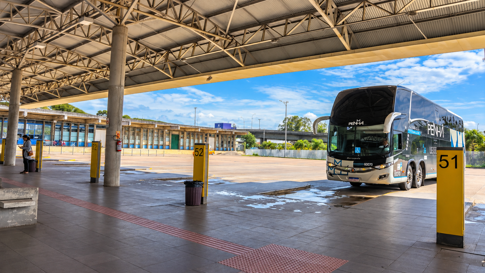 Ônibus rodoviário de dois andares da empresa Penha estacionado na plataforma 51 da Rodoferroviária de Curitiba, sob a cobertura do terminal de passageiros.