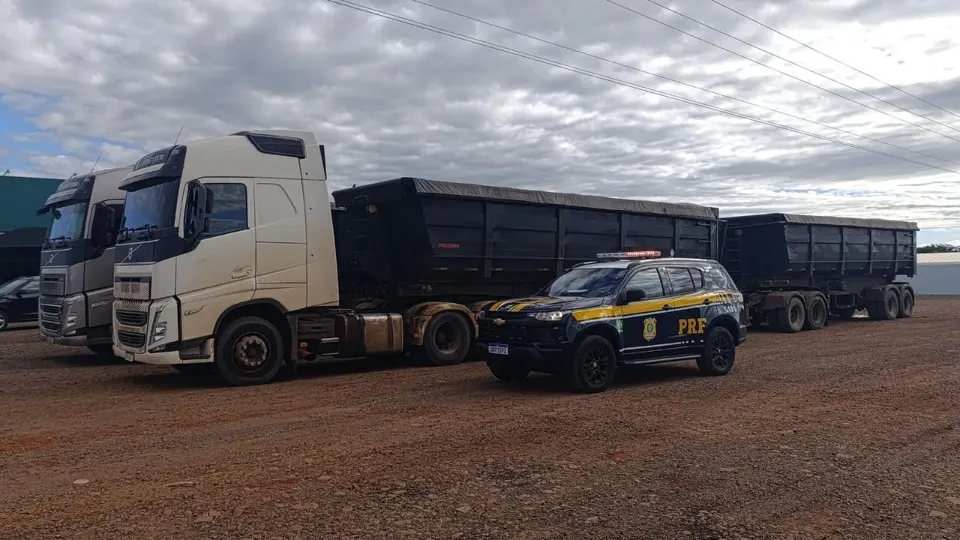 Caminhão bitrem e viatura da Polícia Rodoviária Federal durante fiscalização em rodovia do Paraná.