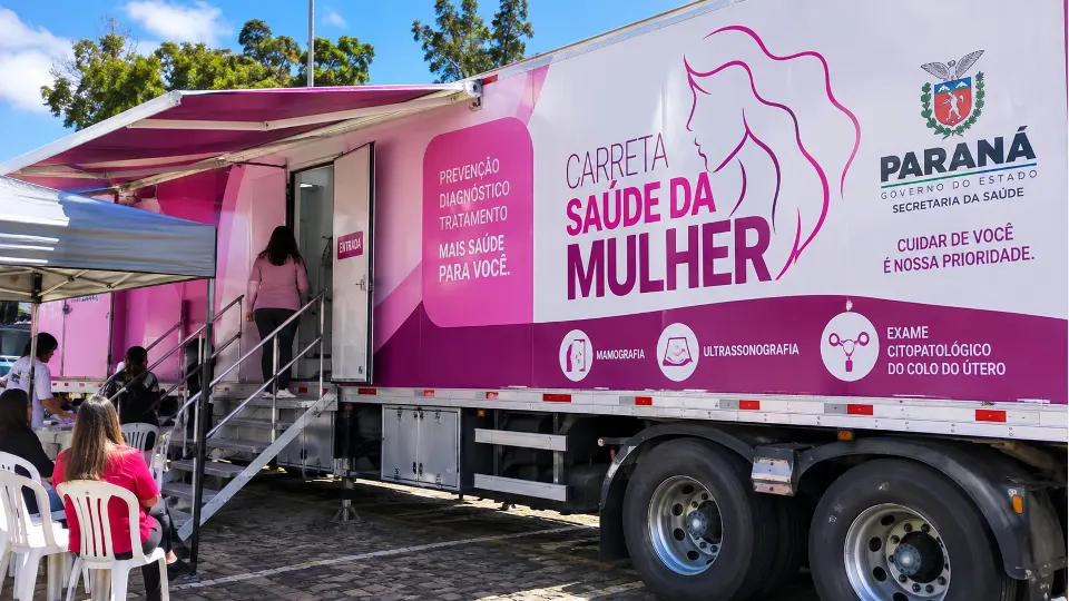 Arte ilustrativa de uma carreta de atendimento à saúde da mulher com serviços de mamografia, ultrassonografia e exame preventivo em Guarapuava.