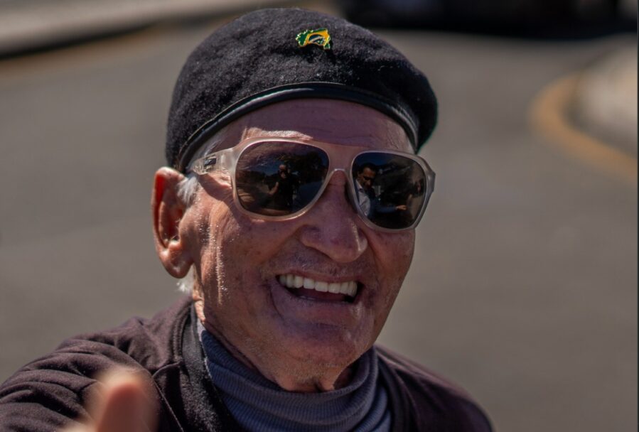 Zé da Bíblia sorrindo e usando boina e óculos escuros em Curitiba.